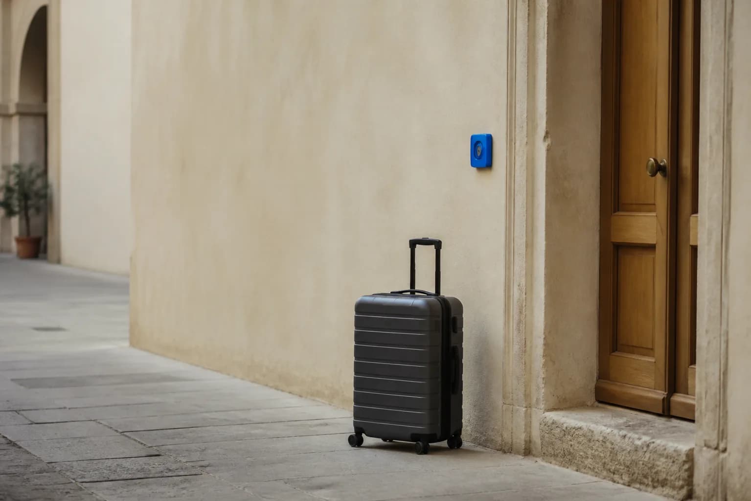 Valigia appoggiata vicino a una porta d'ingresso, luce morbida di fine giornata, nessuna persona.